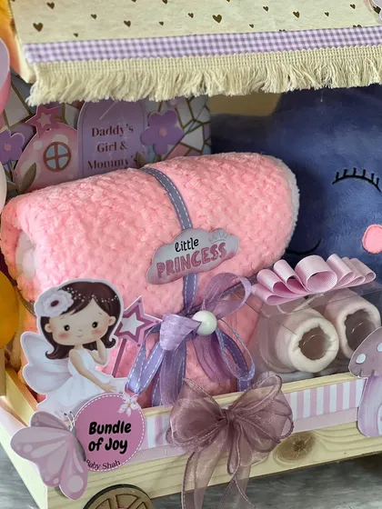 A close-up of the 'Little Princess' trolley hamper. I included a soft pink blanket, baby booties, and lots of fairy and butterfly cutouts to create a magical feel.