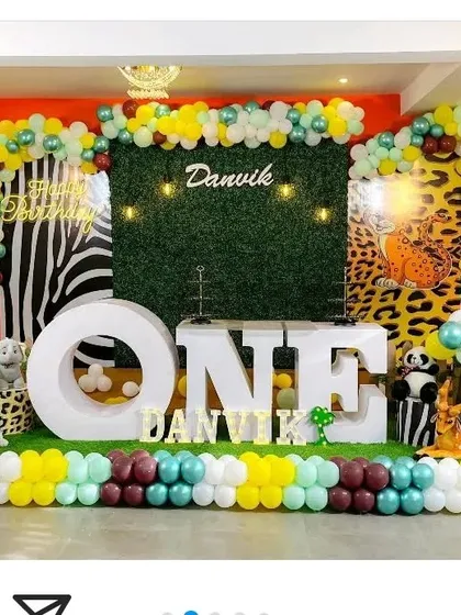 A bold jungle theme using zebra and leopard print backdrops combined with a central grass wall. Large 'ONE' letters serve as the main cake table.