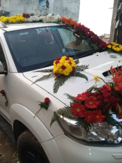 A Toyota Fortuner decorated with bright red and yellow flowers. The arrangement is concentrated on the bonnet and roof, making a bold statement.