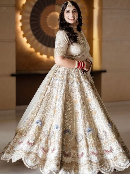 A full-length view of the Anand Karaj bridal look. The ivory and gold lehenga is paired with soft, glowing makeup for a look of serene and timeless elegance.