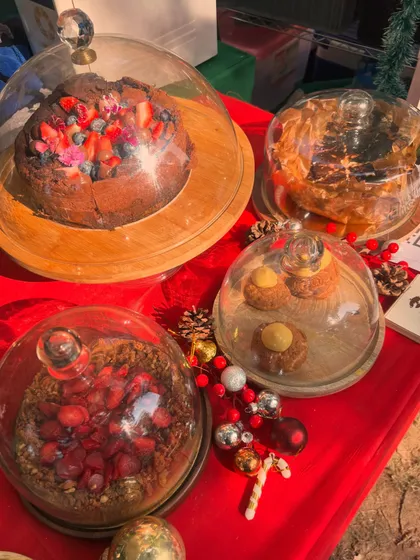 A selection of my desserts, including tarts and cakes, displayed under glass cloches at a Christmas market. It was a lovely day connecting with customers.