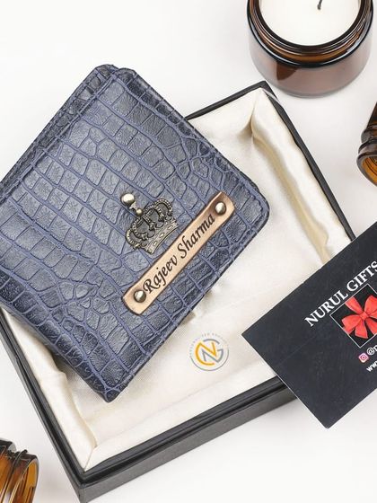 A blue crocodile leather wallet, personalized for 'Rajeev Sharma' with a crown charm.