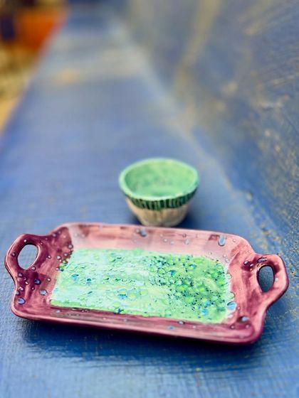 This set, a small bowl and handled tray, is part of my vibrant Kaleidoscope Collection. The contrast between the purple tray and the green bowl highlights my love for playing with bold color combinations in my studio pottery.