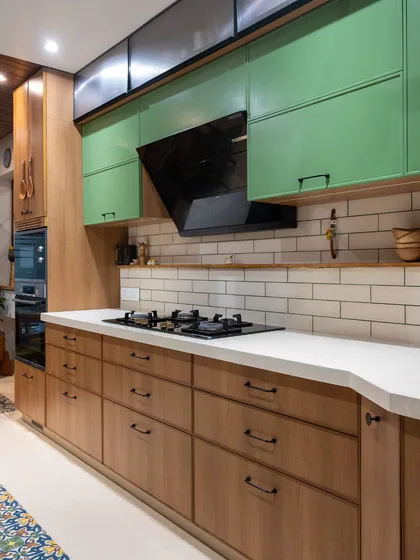 Another angle of the wood and green kitchen, highlighting the ample counter space and the practical layout. The open shelf above the stove keeps essentials handy, blending utility with style.