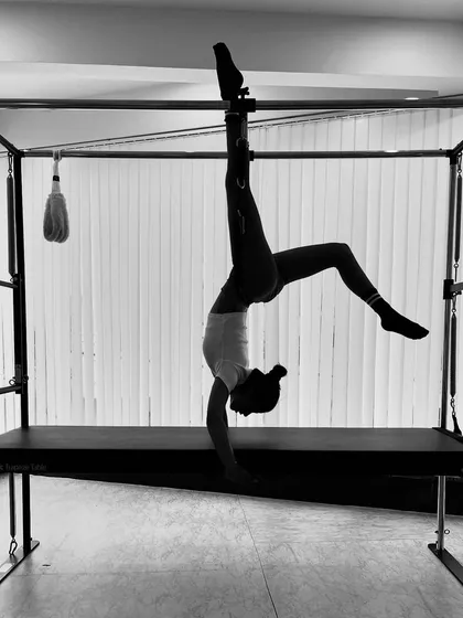A black and white shot capturing the silhouette of an advanced inversion, emphasizing the form and lines of the body.