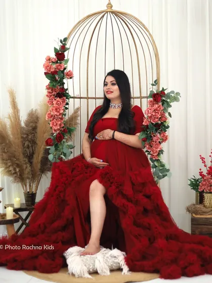 A regal seated pose in a dramatic red gown. This shot highlights the intricate details of the dress and the serene beauty of the mom-to-be.