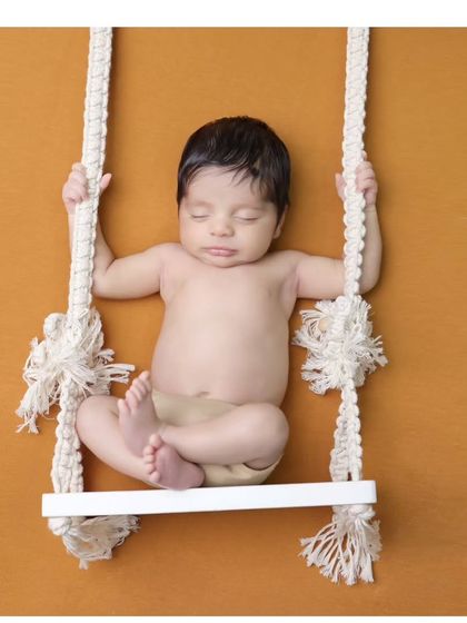 Another take on the swing prop, this time against a warm mustard background. This pose is great for showing the baby's relaxed and sleepy state.
