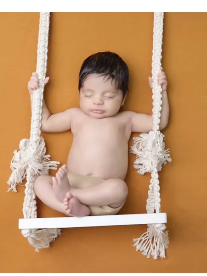Another take on the swing prop, this time against a warm mustard background. This pose is great for showing the baby's relaxed and sleepy state.