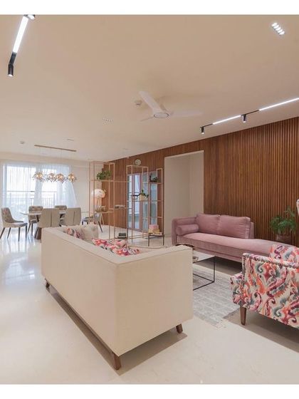 Another view of the living area, highlighting the combination of a plush sofa, a patterned wingback chair, and the warm fluted wood wall. The lighting is designed to be functional and create a warm, inviting ambiance.