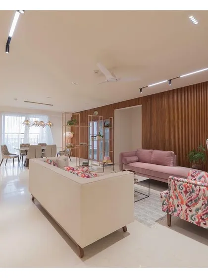 Another view of the living area, highlighting the combination of a plush sofa, a patterned wingback chair, and the warm fluted wood wall. The lighting is designed to be functional and create a warm, inviting ambiance.