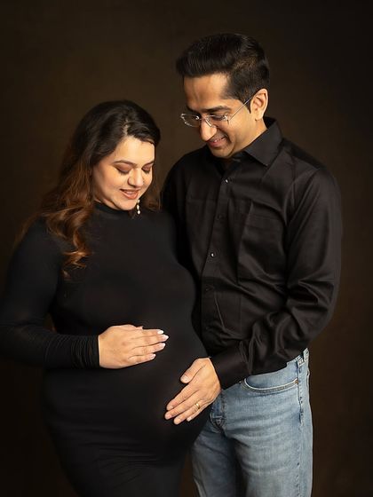 A quiet, tender moment between parents-to-be. The dark, moody background helps to focus all the attention on their expressions and connection.