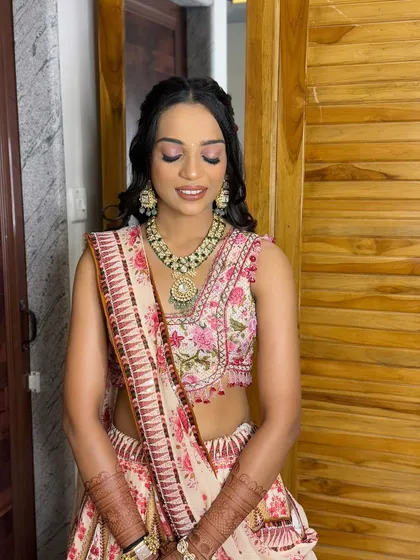 The groom's sister, looking fresh and pretty in a floral lehenga. The makeup is soft and rosy, with a simple, elegant hairstyle.