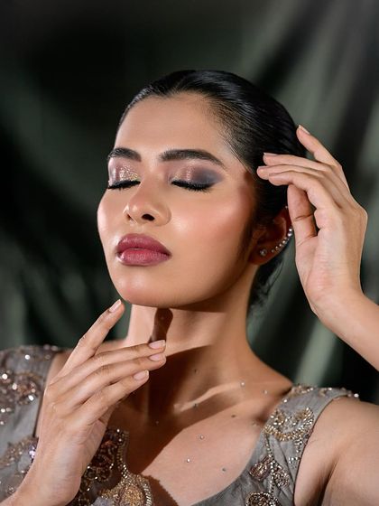 A close-up of a smokey eye look on a model with an embroidered grey top, perfect for editorial or party glam.