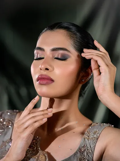 A close-up of a smokey eye look on a model with an embroidered grey top, perfect for editorial or party glam.