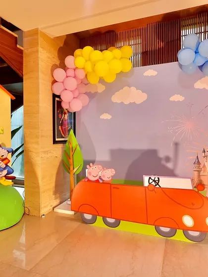 A full shot of the indoor Peppaland party area, showing the house prop, car backdrop, and colorful balloon decorations. This setup is perfect for transforming a living room into a cartoon world.