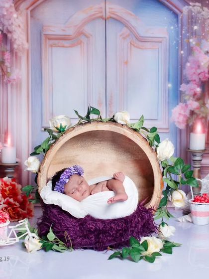 Here, the baby is nestled in a wooden bark bowl, surrounded by flowers and our beautiful floral gate backdrop.