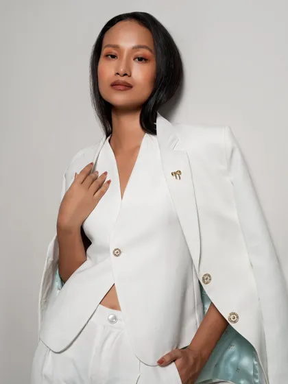 A classic fashion portrait in a white suit. The model's pose and the clean lighting create a look of effortless sophistication, perfect for a professional or formal wear brand.