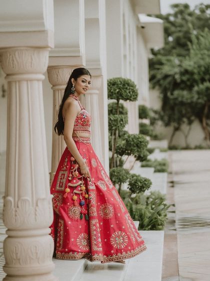 A beautiful shot of a bride at her Mehendi function, wearing our vibrant pink embroidered lehenga. The outfit looks stunning against the architectural backdrop.