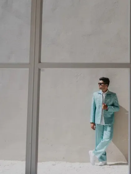 A minimalist and stylish portrait of the groom against a simple wall. This shot highlights his modern, pastel-colored outfit and our eye for clean, architectural compositions.