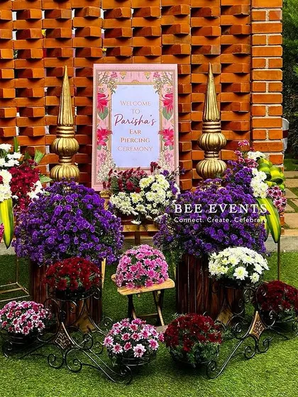 A beautiful welcome arrangement for an outdoor event. We used a rich palette of purple and pink flowers, combined with traditional brass props, to create a vibrant and inviting display for guests.