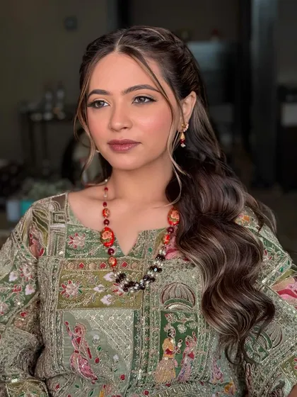 The bride's Mehendi look from another angle, showcasing the soft waves in her hair and the flawless finish of her makeup.