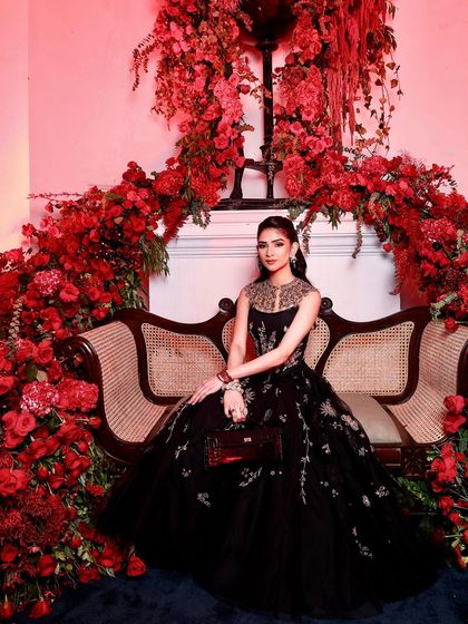 Another stunning portrait against the floral wall. The red lighting adds a dramatic flair, making the makeup look even more striking and glamorous.