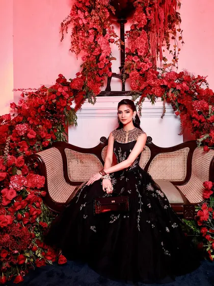 Another stunning portrait against the floral wall. The red lighting adds a dramatic flair, making the makeup look even more striking and glamorous.