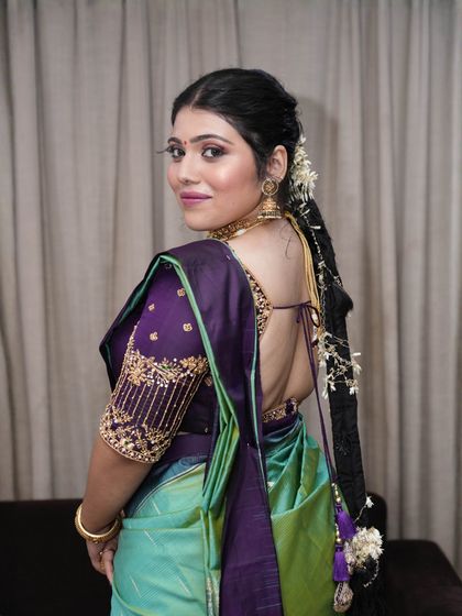 This shot showcases the beautiful back details of the blouse and the traditional long braid. The bride's skin has a soft, velvety finish.