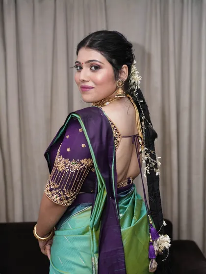 This shot showcases the beautiful back details of the blouse and the traditional long braid. The bride's skin has a soft, velvety finish.