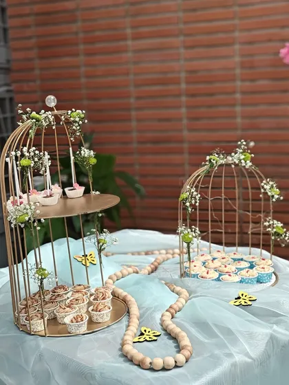 We bring the sweetness to your celebration with our elegant dessert table setups. This display, featuring a variety of our cupcakes and treats in decorative birdcages, was designed for a beautiful outdoor party.