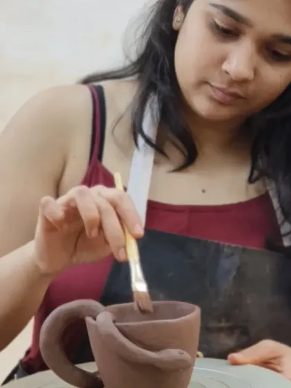 A student applies a finishing touch to her mug, which features a unique snake-shaped handle. Our classes encourage creative expression and the development of a personal artistic style.