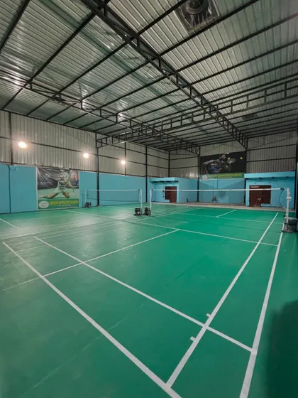 A clear, wide view of our new, professionally maintained indoor badminton court at the Sector 9B Gurugram center, featuring green synthetic mats and excellent overhead lighting.