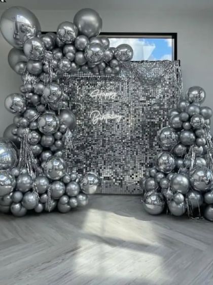 An all-silver setup with a sequin wall and massive balloon arrangements, creating a futuristic and high-impact look.