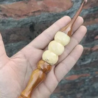 This hook features a handle made with beautiful, creamy white beads. It provides a unique grip and adds a touch of elegance to your crochet tool collection.