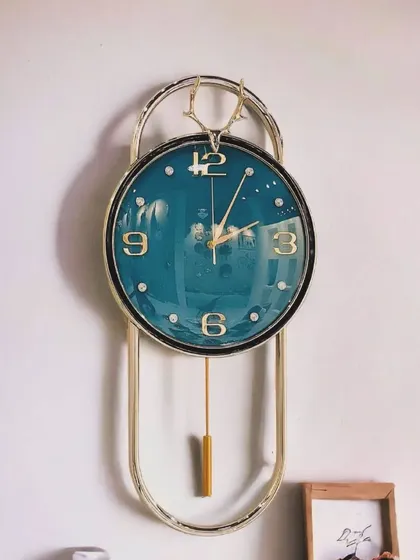 This imported wall clock features a deep blue face, offering a cool and calming aesthetic. The design is accented with a deer-head motif and a gentle pendulum, blending classic elegance with a touch of contemporary style.