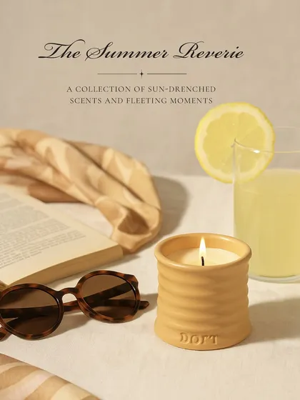 The Summer Reverie: a collection of sun-drenched scents and fleeting moments. This image captures that feeling, a half-read novel and a glass of lemonade, accompanied by the soft glow of my Daydream ceramic candle.