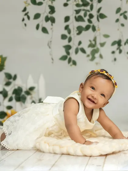 A happy baby crawling on a cozy woven mat in a garden-themed set. The combination of textures and simple props creates a beautiful and engaging environment for a sitter session.