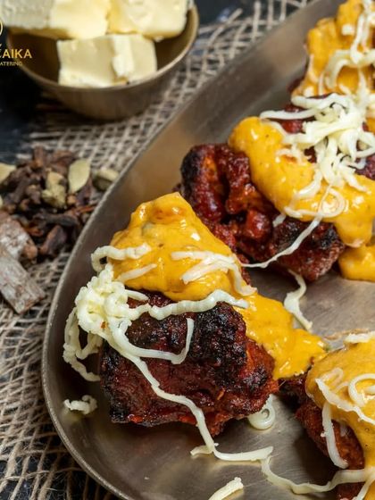 A close-up of our Mutton Cheese Overload, showing the perfectly charred mutton pieces peeking through a generous layer of melted cheese sauce and shredded cheese.