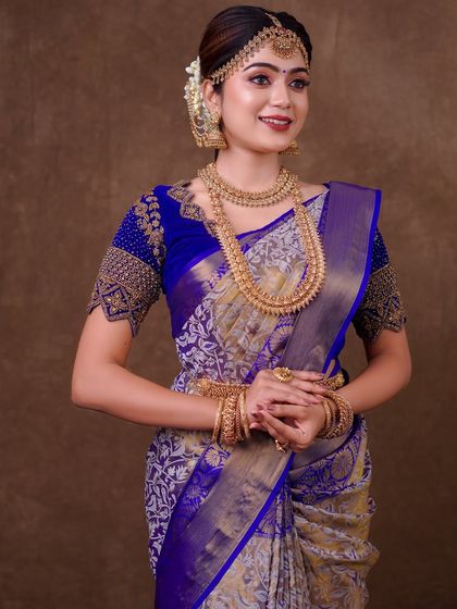 A royal blue and silver brocade saree. The draping here is all about showcasing the richness of the fabric, with a neatly pleated pallu and a full, grand silhouette.