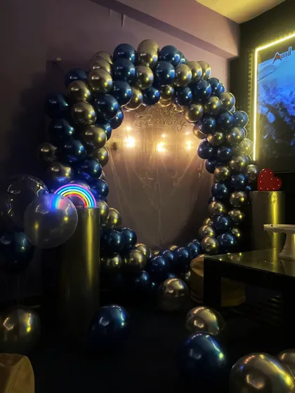 A full view of the circular balloon arch in metallic blue and silver, complete with a rainbow light prop for a touch of fun.