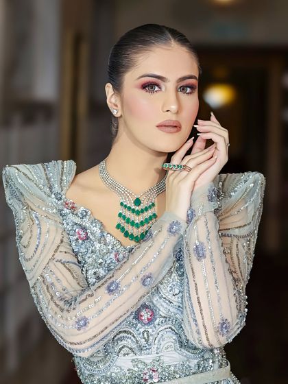 Another pose in the silver-blue gown, this time with hands framing the face to draw attention to both the makeup and jewelry.