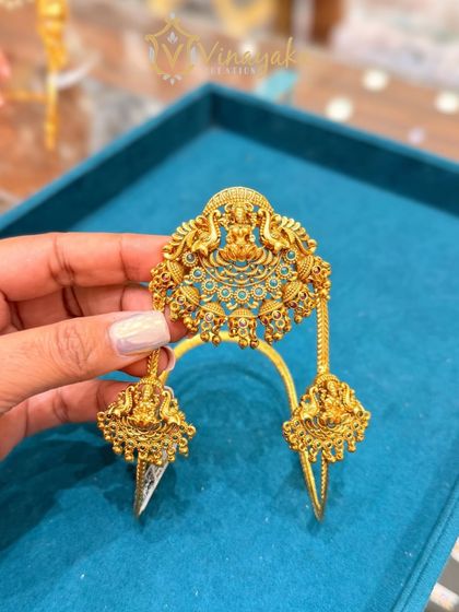 This bajuband features a unique design with three distinct temple motifs. The central piece is larger, creating a very grand and traditional look for a bride.