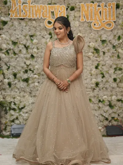 A full-length view of the bride's stunning beige engagement gown with intricate beadwork. The makeup is sophisticated and polished.