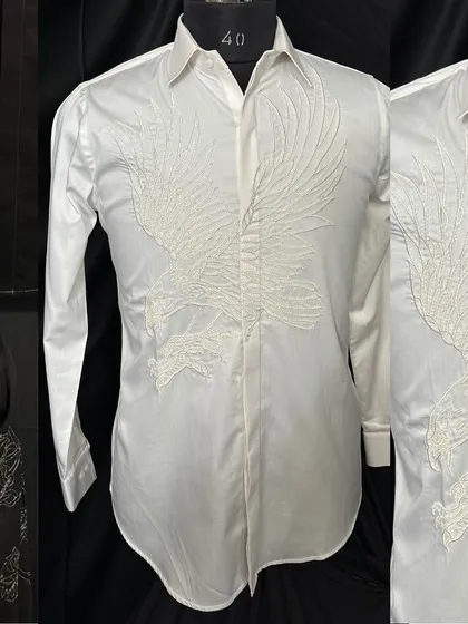 A stunning white shirt with a large, embroidered eagle spreading its wings across the front. This piece is a statement of power and elegance, designed for those who value artistic detail.