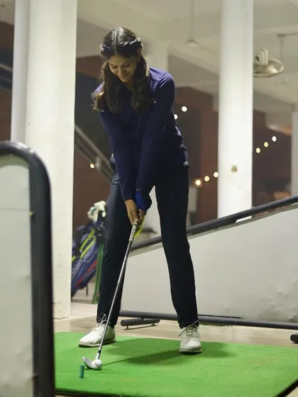 A player focusing on her stance before swinging into the weekend. Our range is a popular spot for golfers of all genders and skill levels.