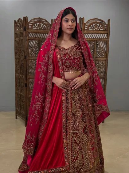 This deep red velvet lehenga features intricate paisley and floral embroidery, perfect for a winter wedding.