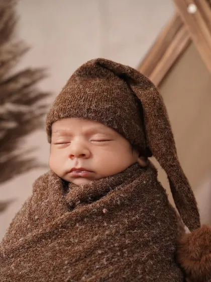 This shot captures the full setup of the camping theme, with the baby swaddled comfortably and the rustic props creating a warm, earthy feel.
