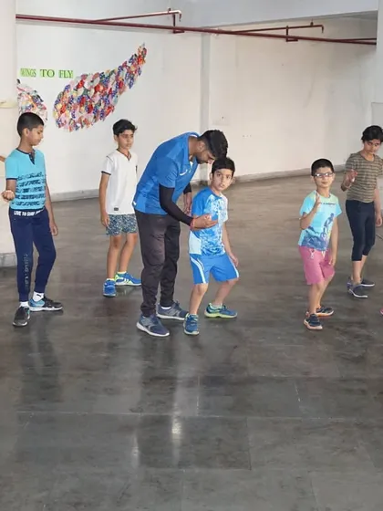 A coach correcting the stance of a young camper. Our summer camp provides personalized attention to ensure everyone learns the fundamentals correctly.