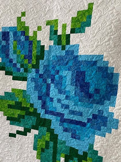 A close-up of the pixelated rose quilt, showing how individual squares of color blend to form a larger image.