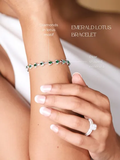 The Emerald Lotus Bracelet worn on the wrist. This design features pear-shaped emeralds and diamonds set in a delicate lotus motif, symbolizing purity and beauty.